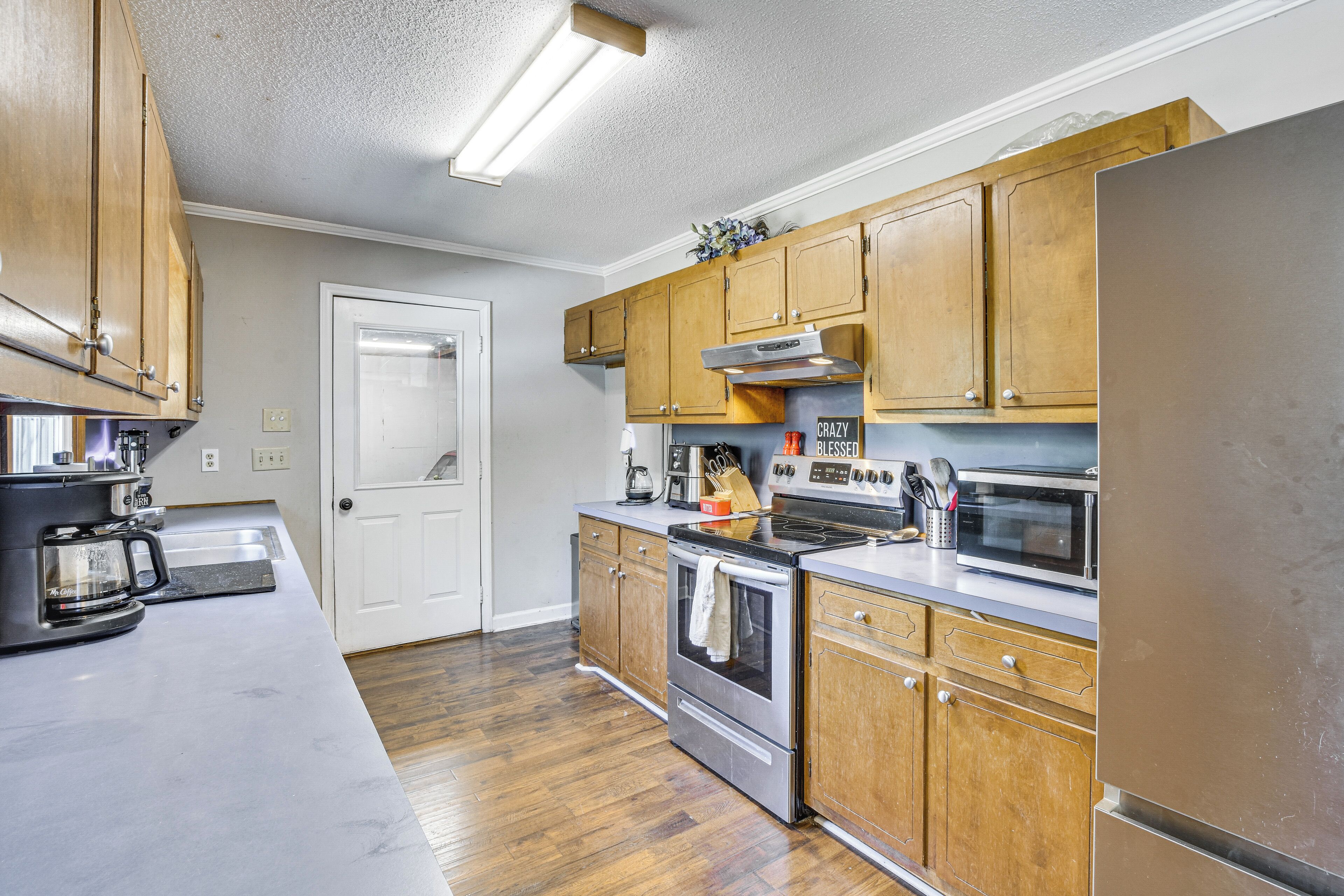 A kitchen with wooden cabinets, stainless steel appliances, and a white countertop.