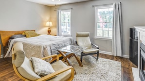 Une chambre à coucher comprenant un lit, deux chaises, une table, un ventilateur de plafond et une cheminée.