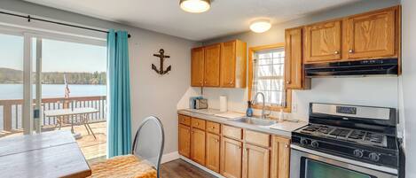 Una cocina con armarios de madera, una estufa y vistas al exterior.