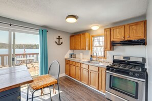 A kitchen with wooden cabinets, a stove, and a view of the outdoors. - Waterfront Cabin w/ Boat Slip & Views in Croton! (Newaygo)