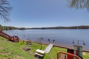 A lakeside view with a wooden dock, a picnic table, and a metal railing. - Waterfront Cabin w/ Boat Slip & Views in Croton! (Newaygo)