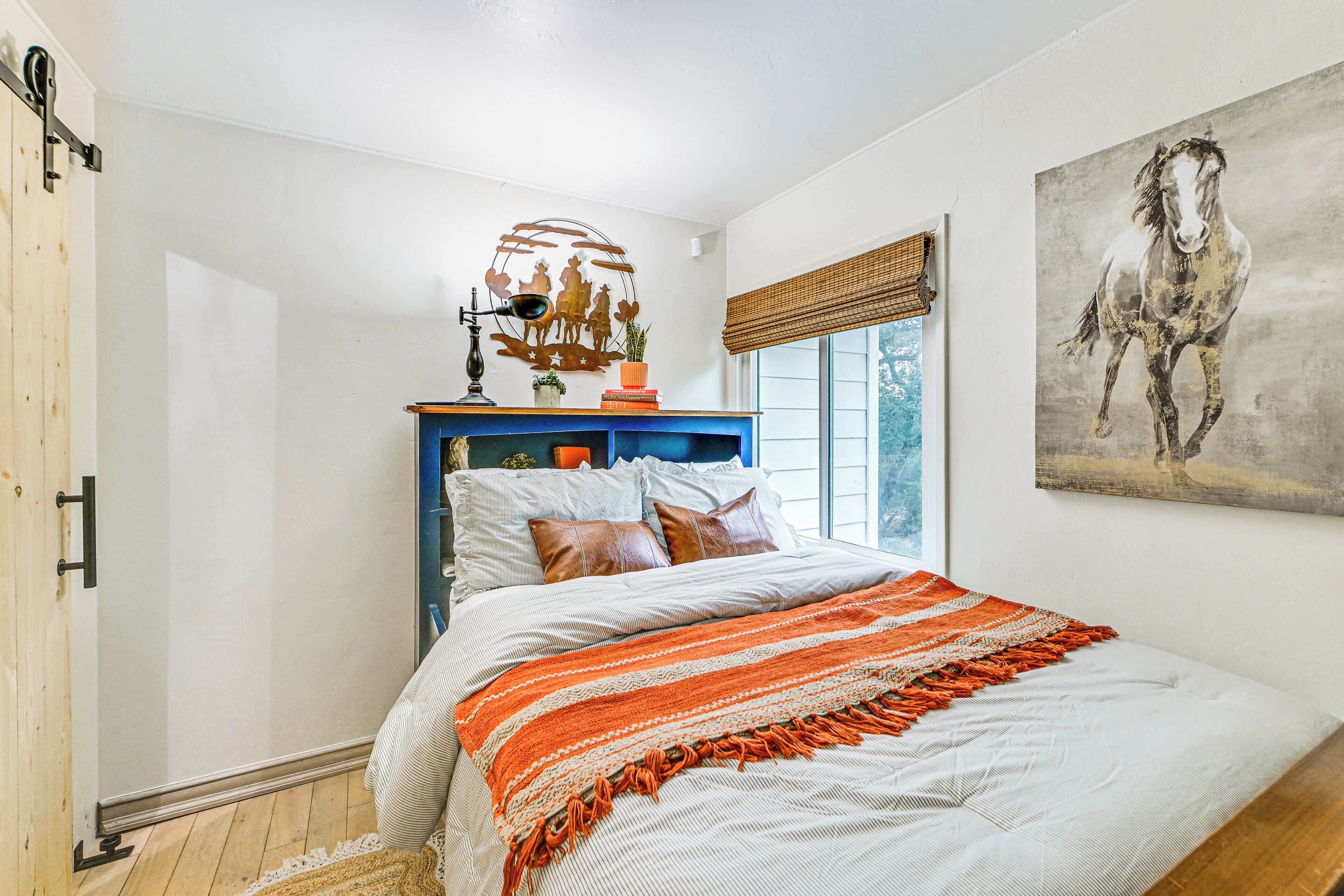 Un dormitorio con cama, cómoda, ventana con vistas y un cuadro en la pared.
