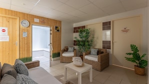 Um saguão de hotel com balcão de recepção, móveis de vime, um relógio e uma placa indicando o banheiro feminino.