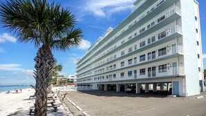 Ein mehrstöckiges Hotel mit Balkonen, einem Parkplatz und Blick auf den Strand.