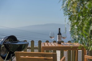 A wooden table with a bottle of wine and two glasses, a grill, and a view of the sea. - Loft the Ma-Air-BBQ (Adeje)