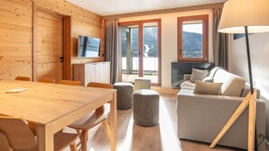 A wooden interior with a dining table, sofa, TV, and large windows. - 6-person Apartment Near Ski Lifts (Vaujany)