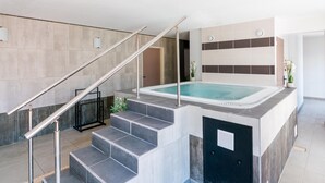 Un espace piscine intérieur moderne, avec un escalier menant à un espace de détente, un panneau de commande et une plante en pot.