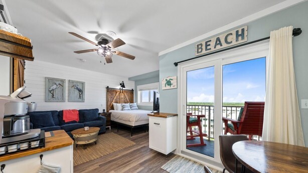 A cozy room with a bed, a sofa, a dining table, and a kitchen area. - Coastal Gulf Front Studio in Fort Morgan | Sleeps 4 (Gulf Shores)