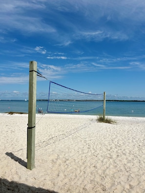 Een strandvolleybalnet op een zandstrand met een heldere lucht.