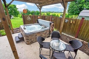 A hot tub with stone exterior, surrounded by wicker chairs and a glass table, under a wooden pergola. - Luxury Estate with Hot Tub, 9 Hole Frisbee Golf, Fire Pit (Mount Juliet)