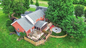 A two-story house with a covered patio, a fenced yard, and a circular fire pit area. - Luxury Estate with Hot Tub, 9 Hole Frisbee Golf, Fire Pit (Mount Juliet)