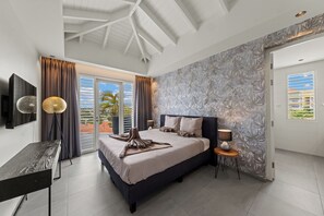 Ein modernes Schlafzimmer mit Bett, Schreibtisch, Lampe und Blick ins Freie.