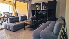 Un salon moderne avec des canapés gris, une table basse et un meuble TV doté d’étagères.