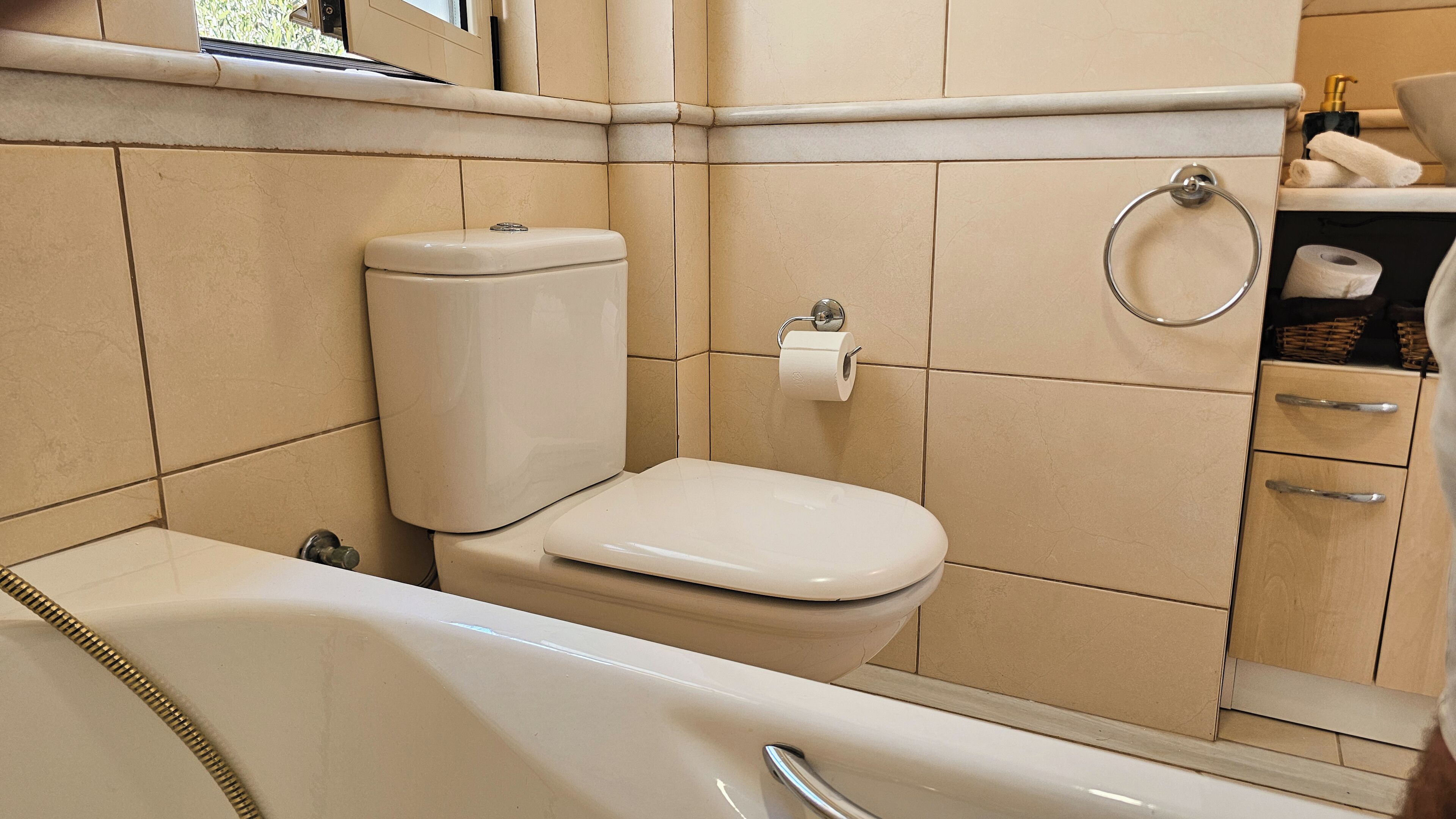 A bathroom with a toilet, a bathtub, and a towel rack.