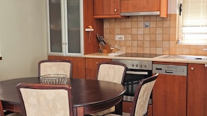 A compact kitchen with a dining table, chairs, a dishwasher, and a stove. - Casa Elysia 3BR with beach and pool (Platanias)