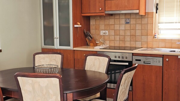 Une cuisine compacte comprenant une table à manger, des chaises, un lave-vaisselle et une cuisinière.