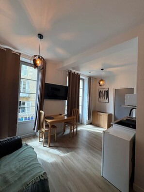 A compact living space with a dining area, kitchenette, and a TV mounted on the wall. - Studio in the heart of historic Sarlat (Sarlat-la-Canéda)