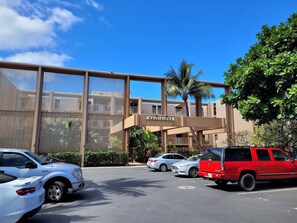 A parking lot with cars, a building with a sign reading 'Kaleidoha,' and a palm tree. - Maui Get-away.  1 BR condo with pool (Lahaina)