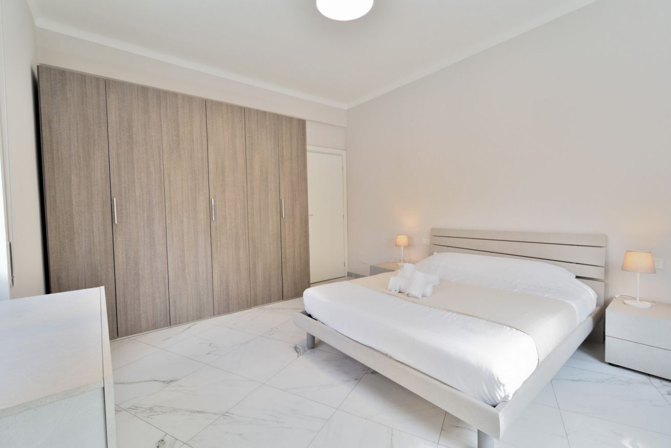 Un dormitorio con una cama grande, un armario y dos lámparas de noche.