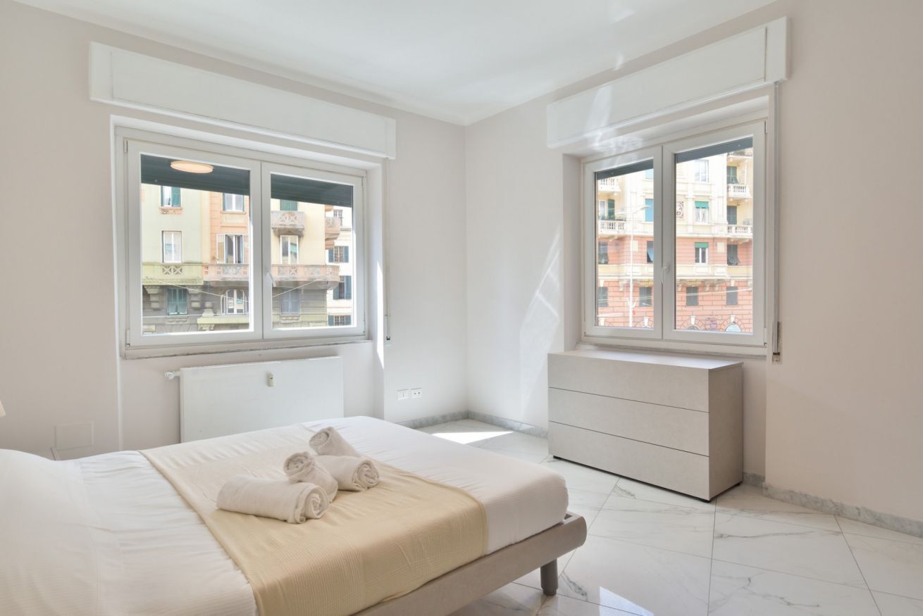A bedroom with a bed, a radiator, a window, and a dresser.