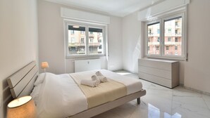 A bedroom with a bed, bedside lamp, windows, and a radiator. - Bright and spacious apartment of approximately 80 square meters, perfect for four people, located on the first floor of a building with an elevator (NOT accessible to disabled guests).The property is located in the Sampierdarena neighborhood, one of the  (Genova)