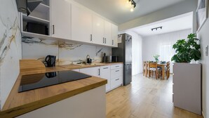 Una cocina moderna con armarios blancos, encimera de madera y un comedor con mesa y sillas.