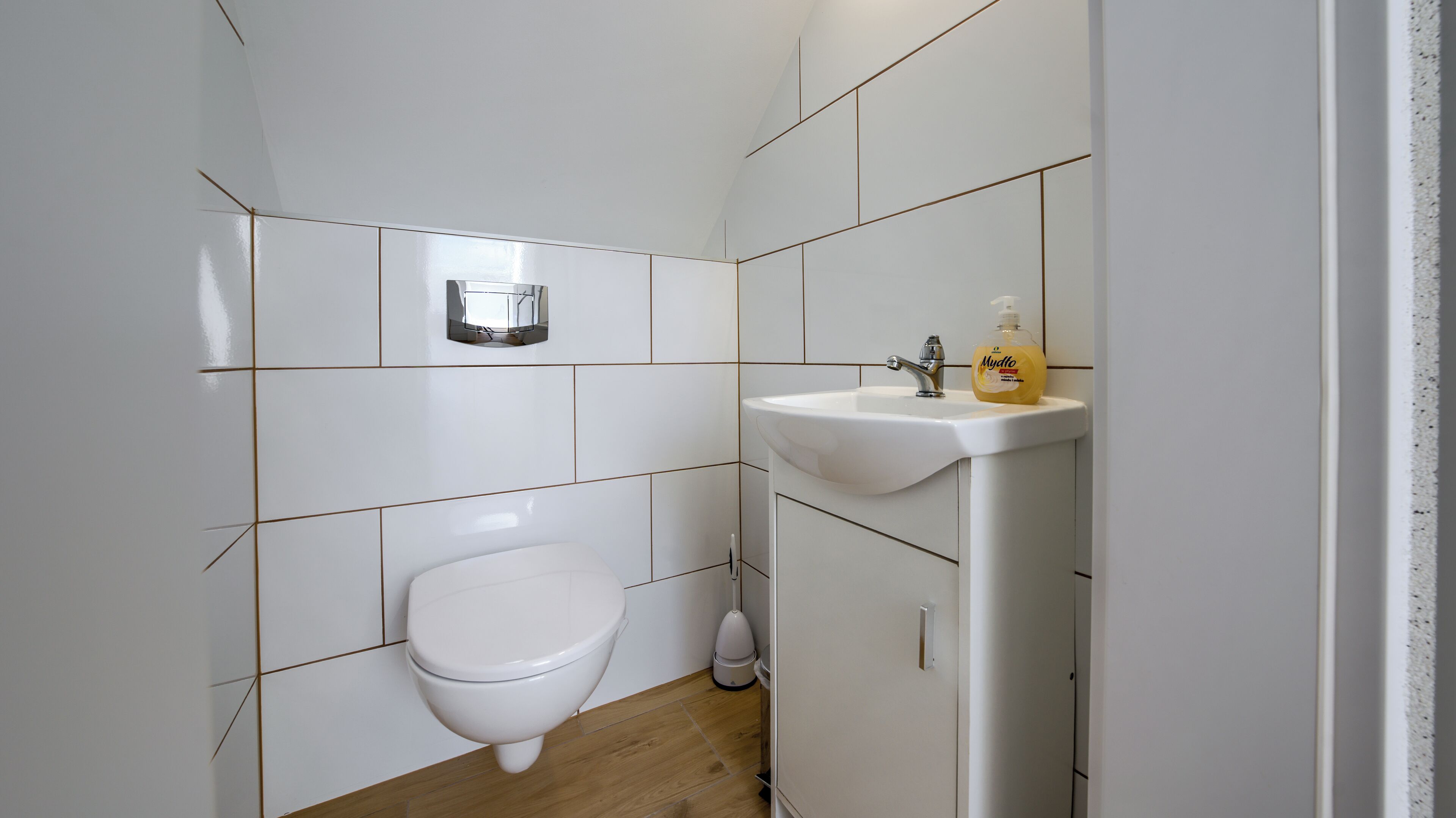 Kylpyhuone, jossa on wc, pesuallas ja käsienkuivaaja.