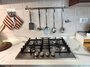 Eine Küche mit Gaskochfeld, einer angebrachten Küchenutensilienstange und einer Steckdose.