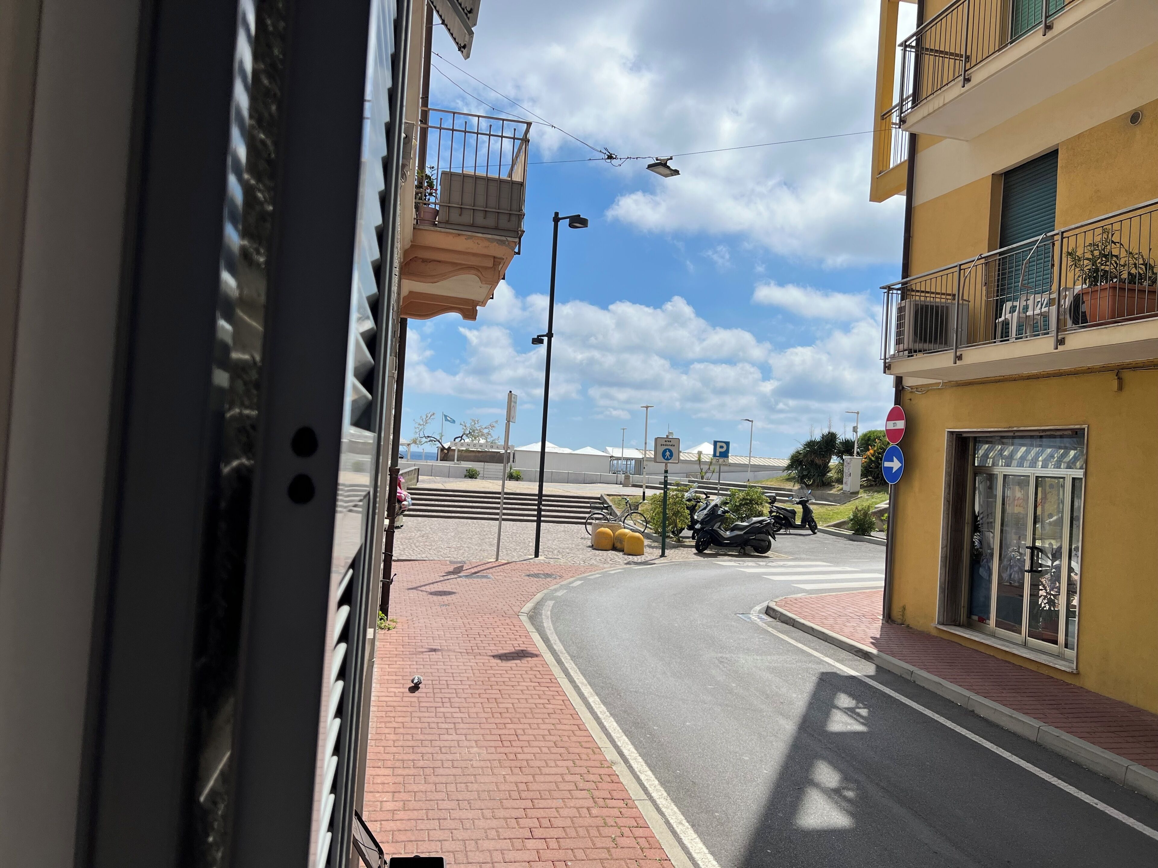 Straßenansicht mit einem Gebäude auf der rechten Seite, blauem Himmel und einem abgestellten Motorrad.