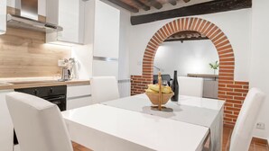 Una cocina moderna con armarios blancos, techo de madera y un arco de ladrillo.