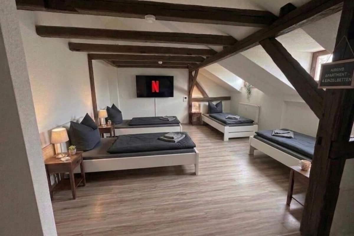 Un dormitorio acogedor en el ático, con techo inclinado, televisor de pantalla plana y un cartel que indica que es un apartamento de Airbnb.