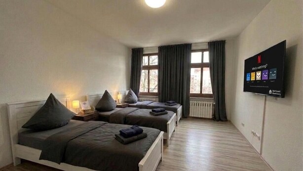 Habitación de hotel con dos camas, televisión y ventana con cortinas.