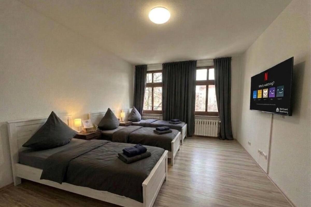 Habitación de hotel con dos camas, televisión y ventana con cortinas.