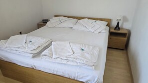 A neatly made bed with white linens and pillows, a bedside table with a lamp, and a wooden nightstand. - Beautiful 2-bedroom apartment with AC in welcoming Gradac (Gradac)