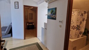 Un pasillo con alfombra estampada, una puerta que da a una habitación, un aire acondicionado instalado en la pared y un cuadro enmarcado.