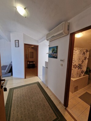 A hallway with a patterned rug, a door leading to a room, a wall-mounted air conditioner, and a framed picture. - Beautiful 2-bedroom apartment with AC in welcoming Gradac (Gradac)