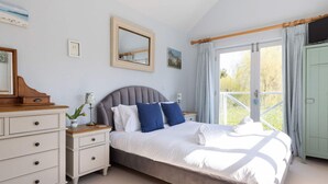 A bedroom with a bed, nightstands, a dresser, a mirror, and a window with curtains. - Stylish Itchenor Home Walk to Harbour Pub (Chichester)