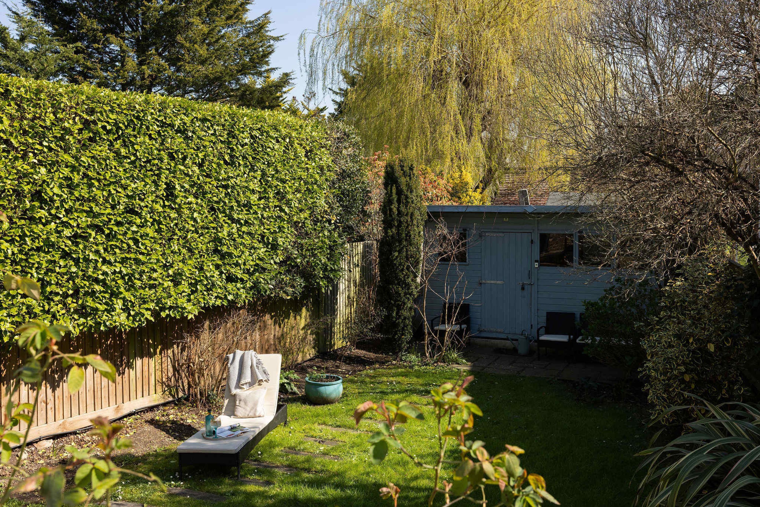 A garden with a wooden fence, a shed, and a bench.