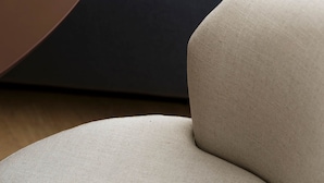 Ein stilvoller Wohnbereich mit einem dunkelblauen Sofa, einem runden, braunen Couchtisch und einem beigen Sessel.