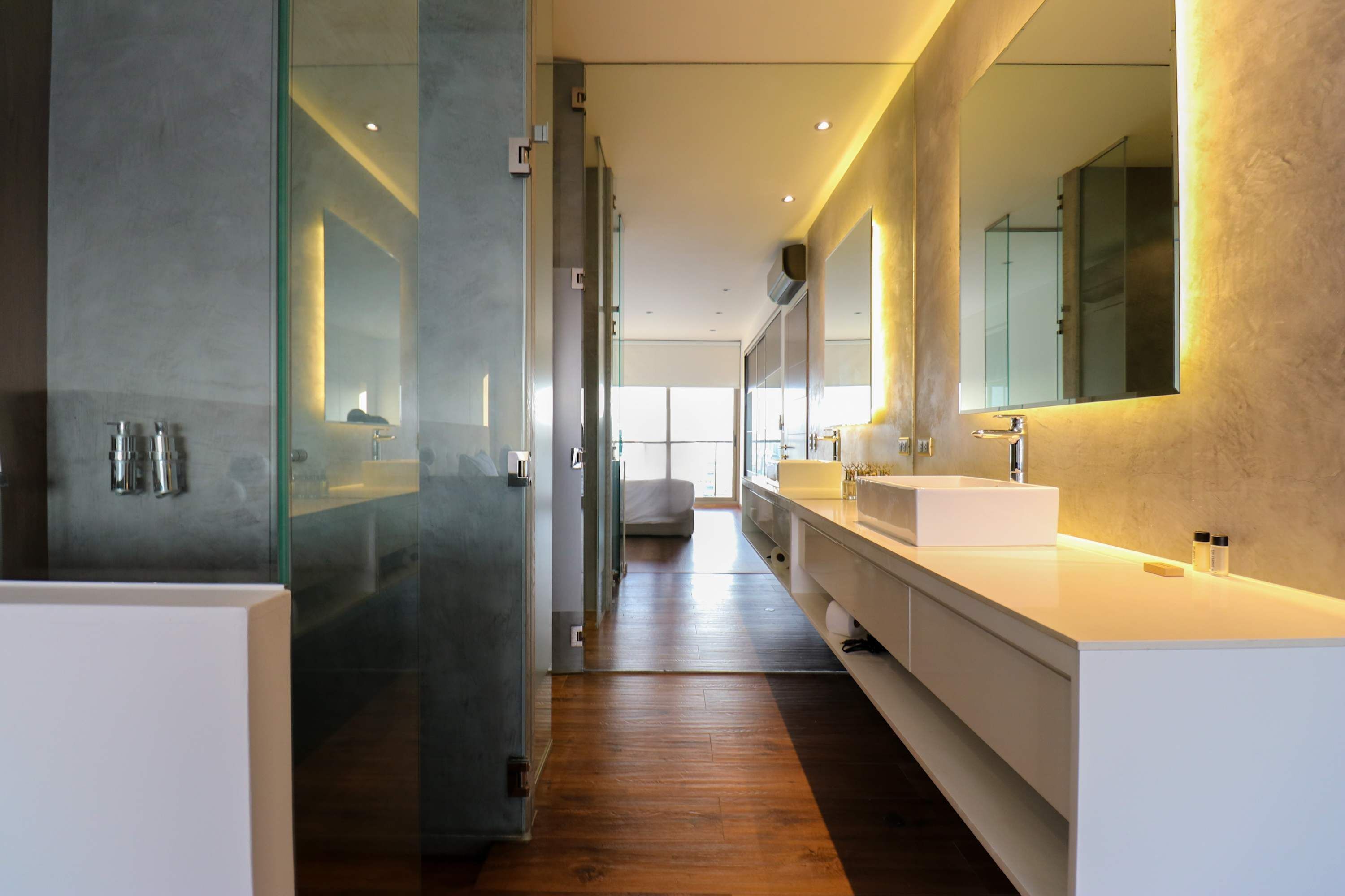 A modern bathroom with a glass shower enclosure, a large mirror, and a long vanity with a sink.