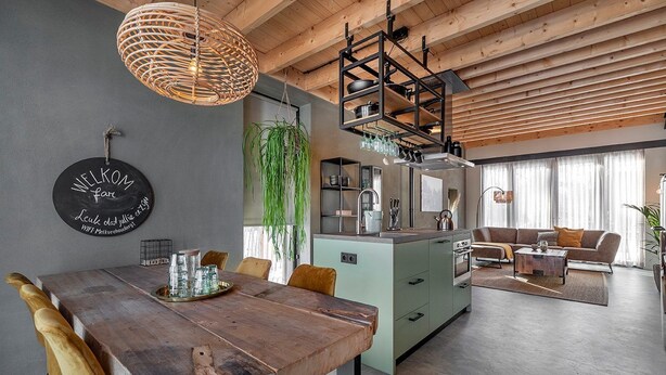Una cocina moderna con una isla central, un comedor con mesa de madera y una sala de estar con sofá.