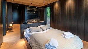 A wooden cabin-style bedroom with a bed, bedside tables, and a built-in bench.