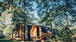 A wooden cabin with a circular exterior, surrounded by trees.