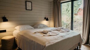 A bedroom with a bed, a bedside lamp, a framed picture, and a window with curtains.