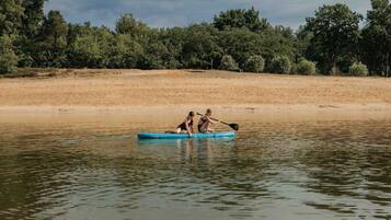 A calm river with a person paddling a blue kayak.