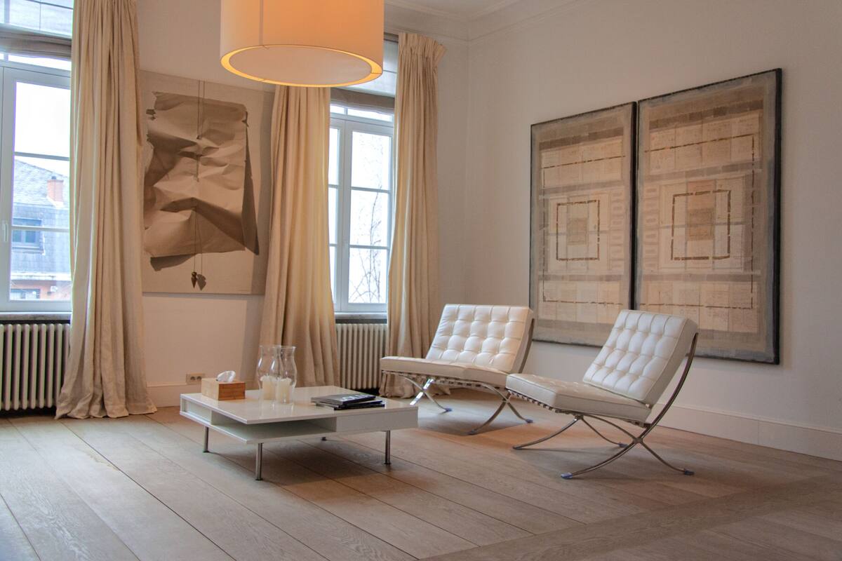 A modern living room with a white sofa, a coffee table, and two abstract paintings on the wall.
