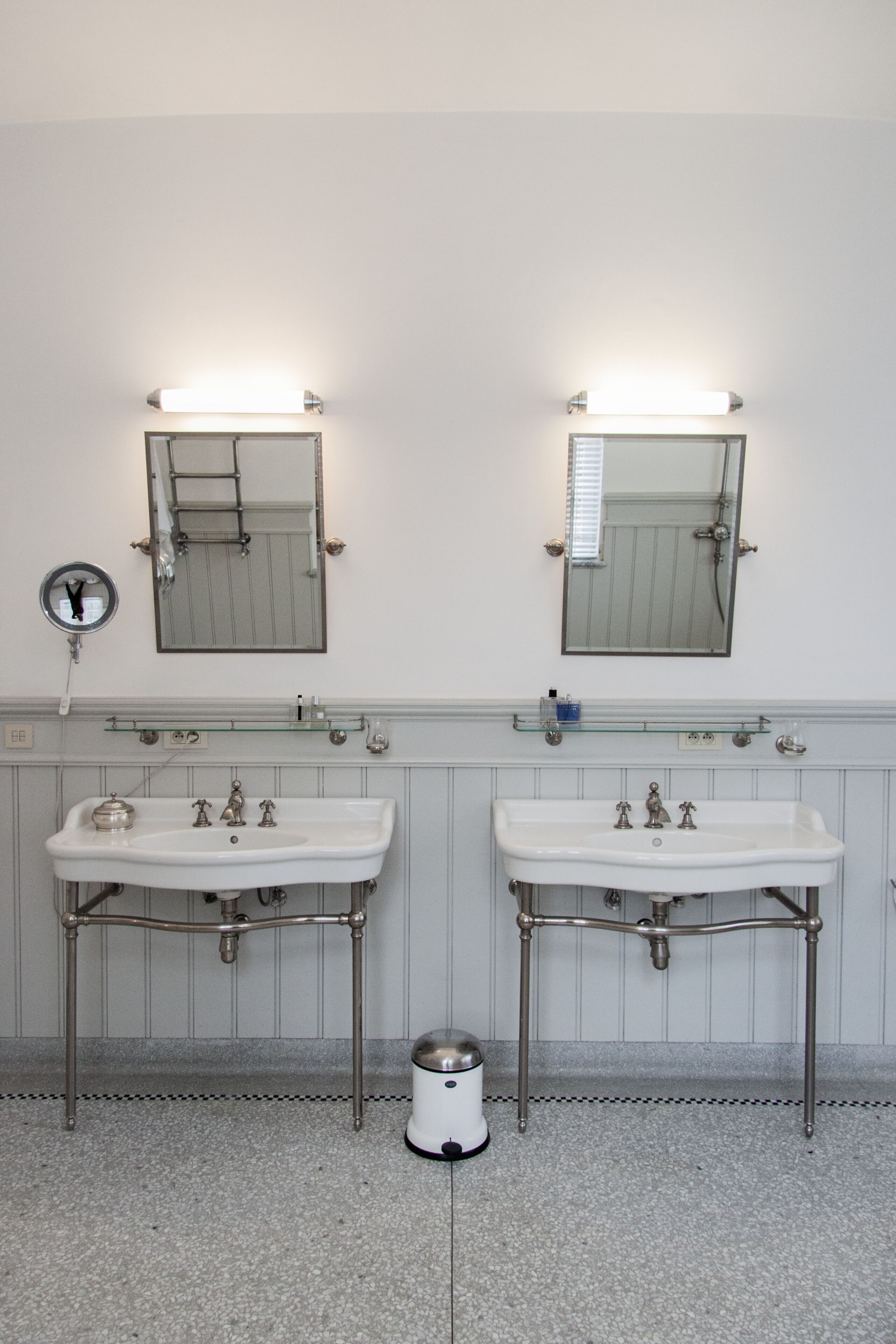 A bathroom with two sinks, mirrors, and a trash can.