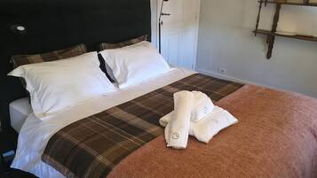 Una cama bien hecha con ropa de cama blanca y marrón, un cabecero y una lámpara de noche.