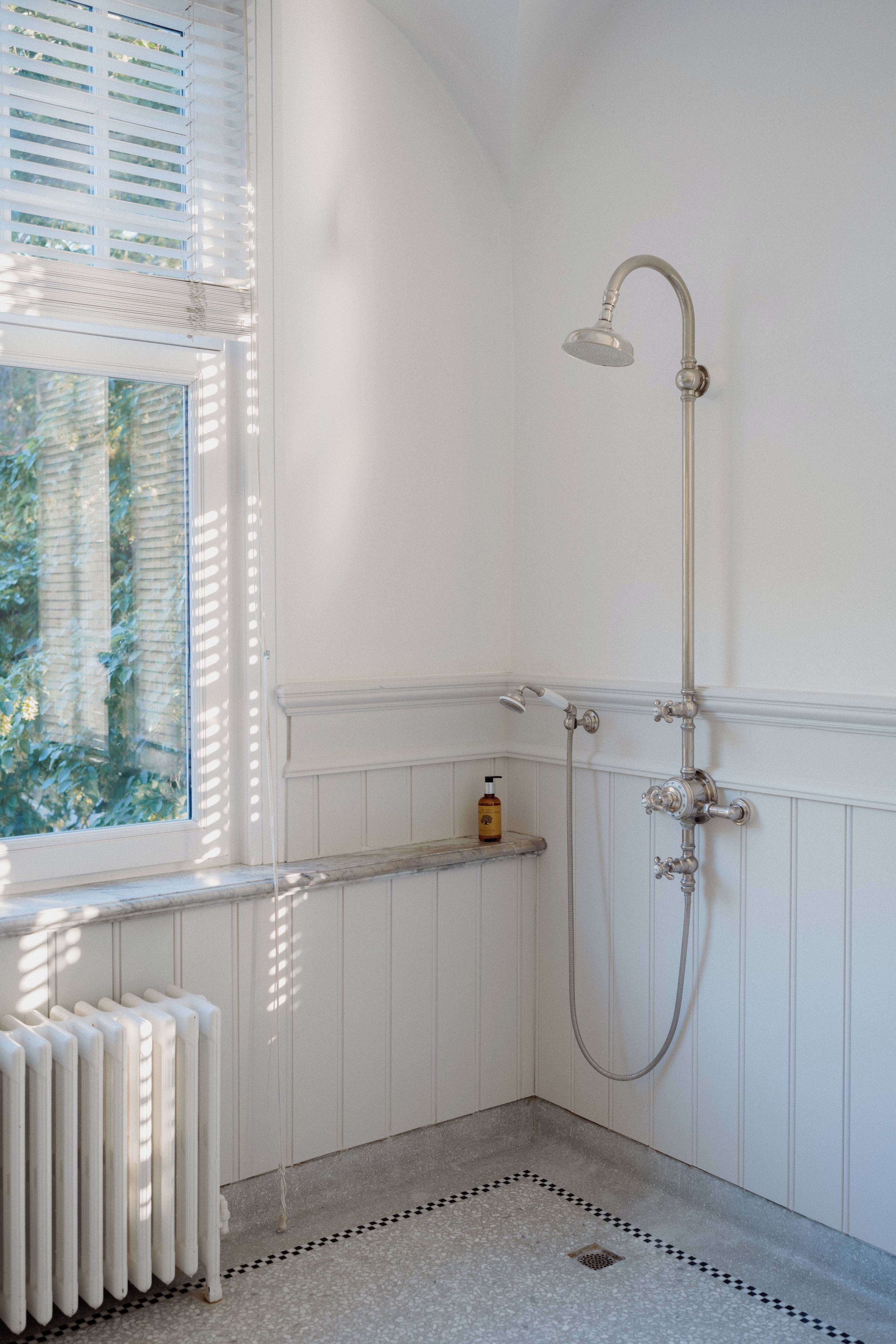 Un baño con ducha, un radiador y una ventana.