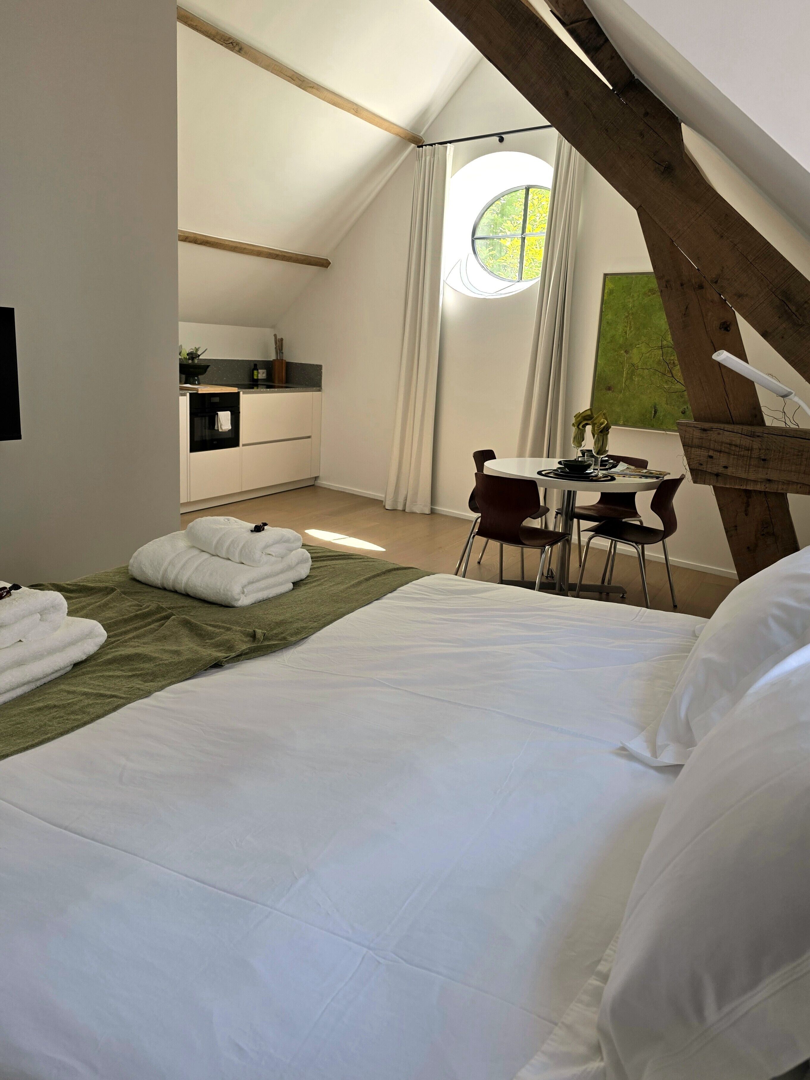 A modern bedroom with a large bed, a dining area, and a kitchen.